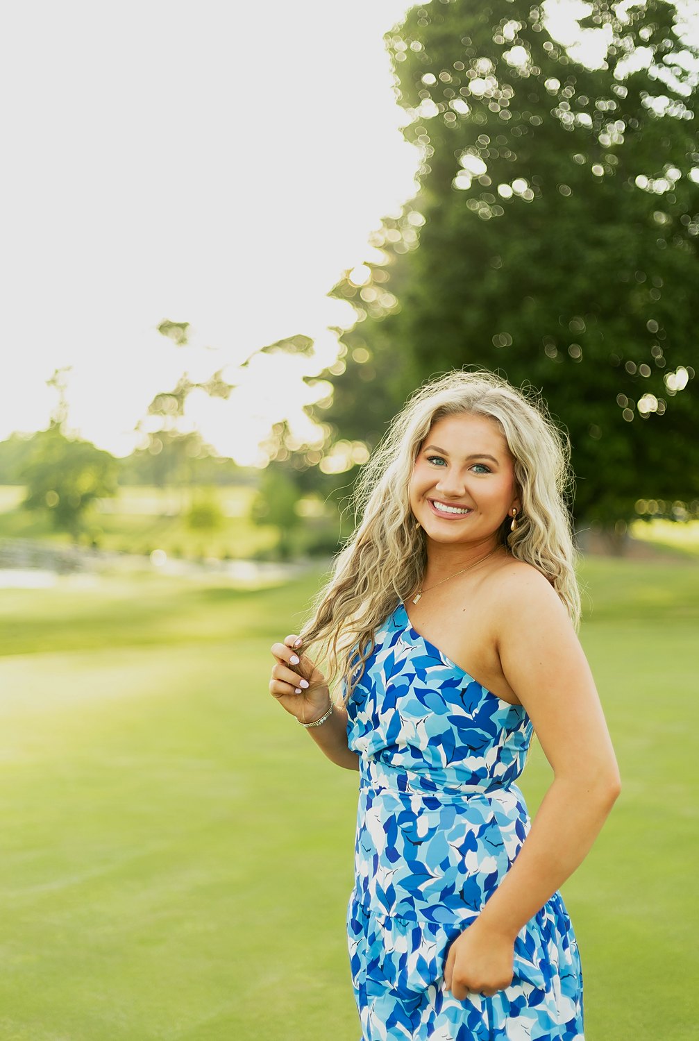 Claire Layne smiling on a golf course at sunset in a blue floral dress