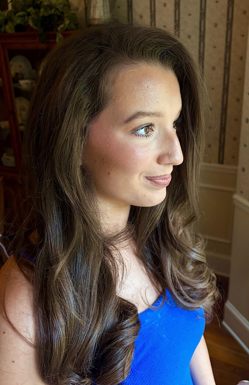 Profile of voluminous brunette curls with soft glam makeup