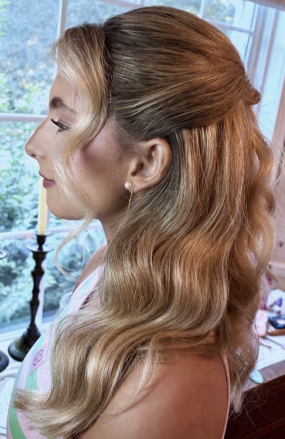 Profile of a half-up style with long waves and a pearl earring
