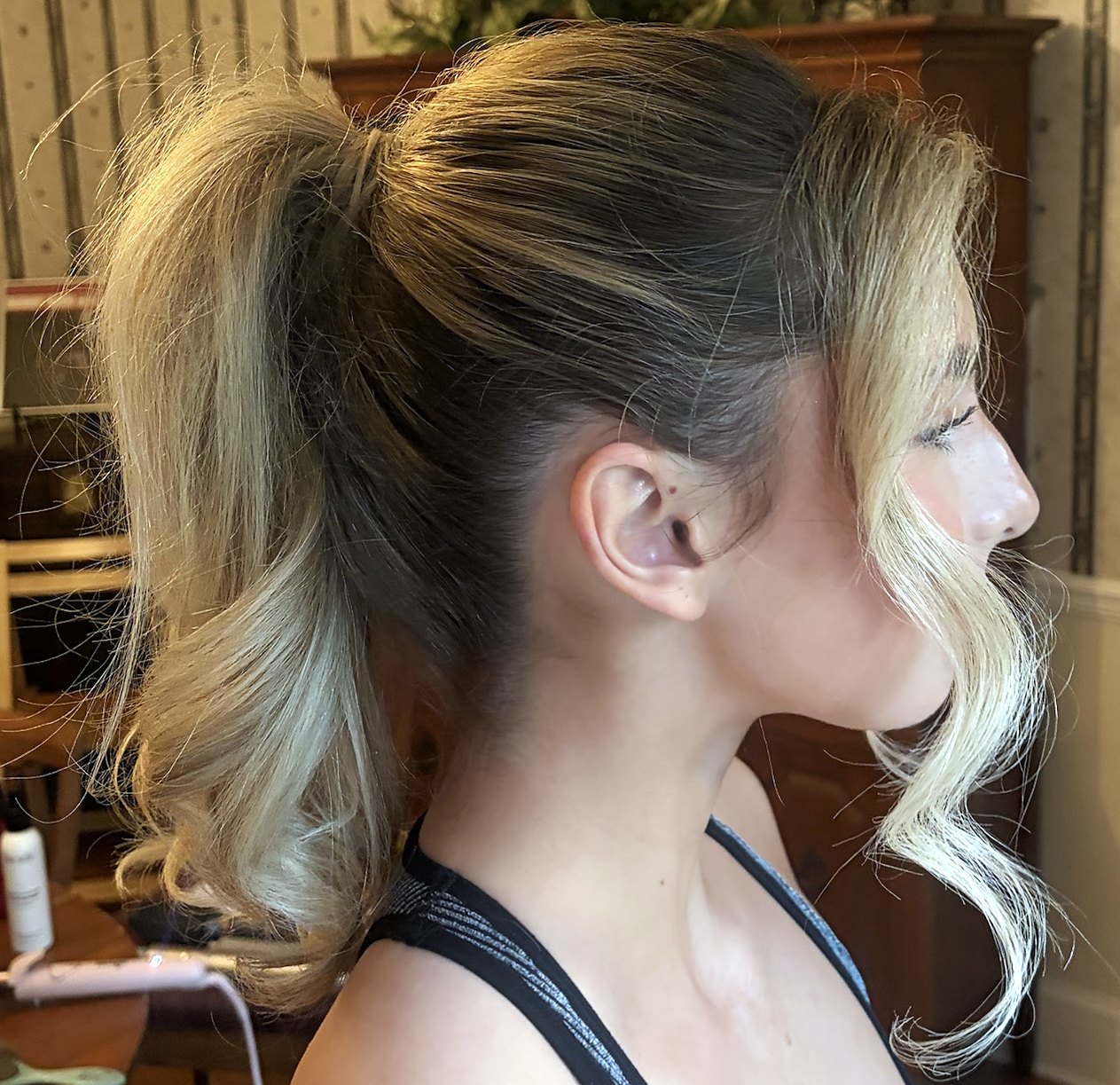 Profile of a high ponytail with curled ends and a face-framing curl