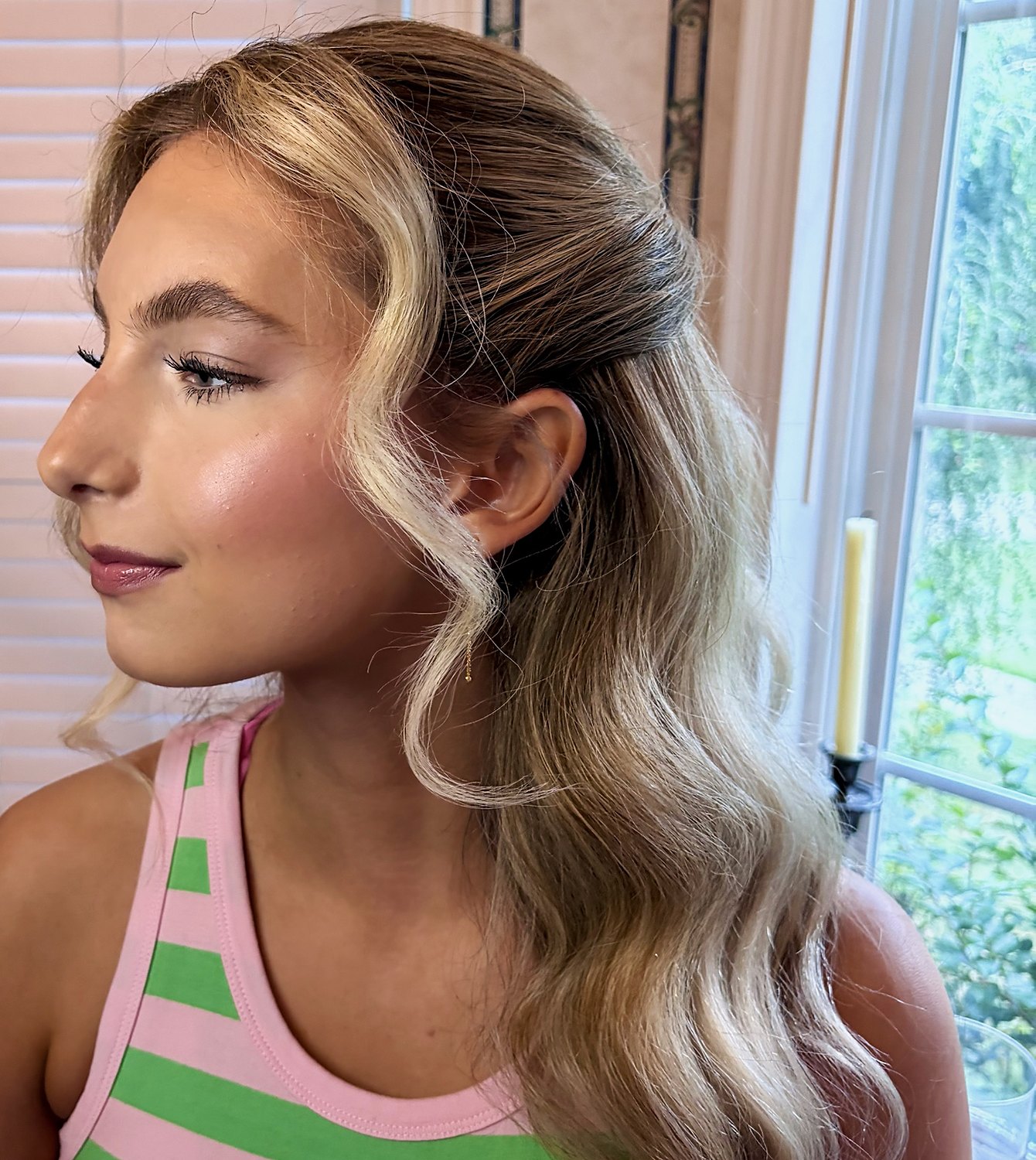 Profile of half-up waves with a face-framing curl and glowing makeup